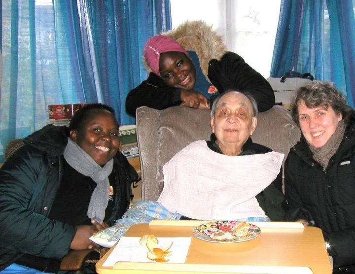A Muzaana carer sharing a meal at the table with a client and her family member.
