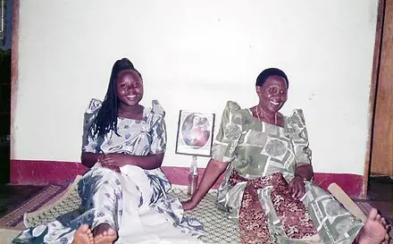 Two women sitting together in a front room during a Muzaana home visit.