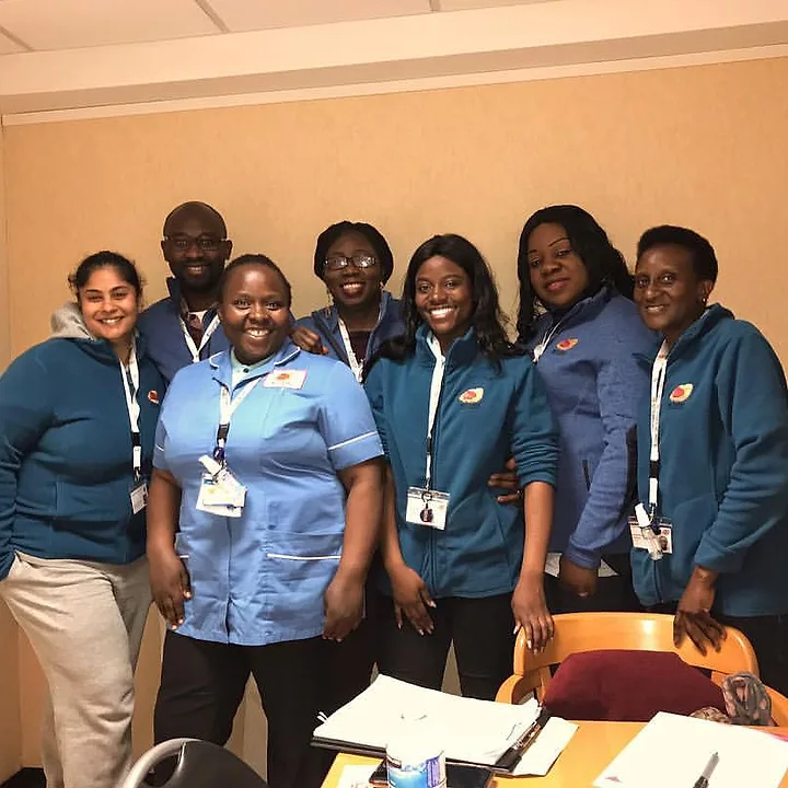 Seven members of the Muzaana team standing together indoors in branded fleeces.