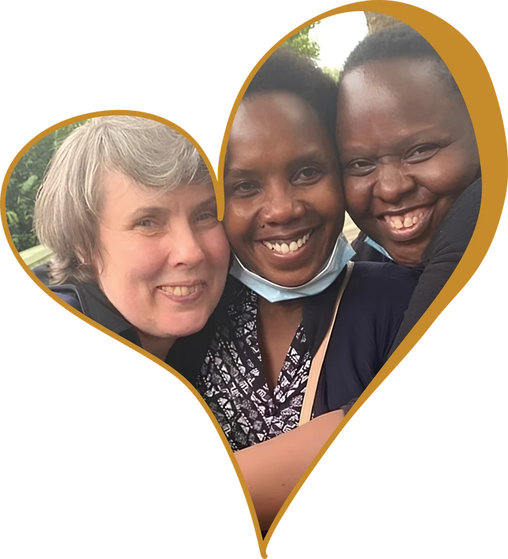 Three women smiling with their heads together, framed in a gold heart.