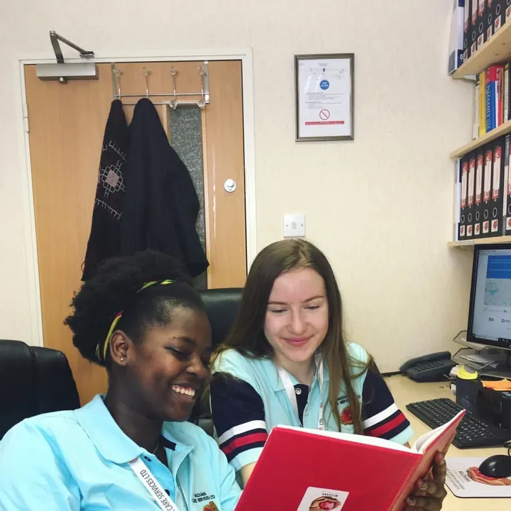 Two Muzaana carers going through a care file together at an office desk.
